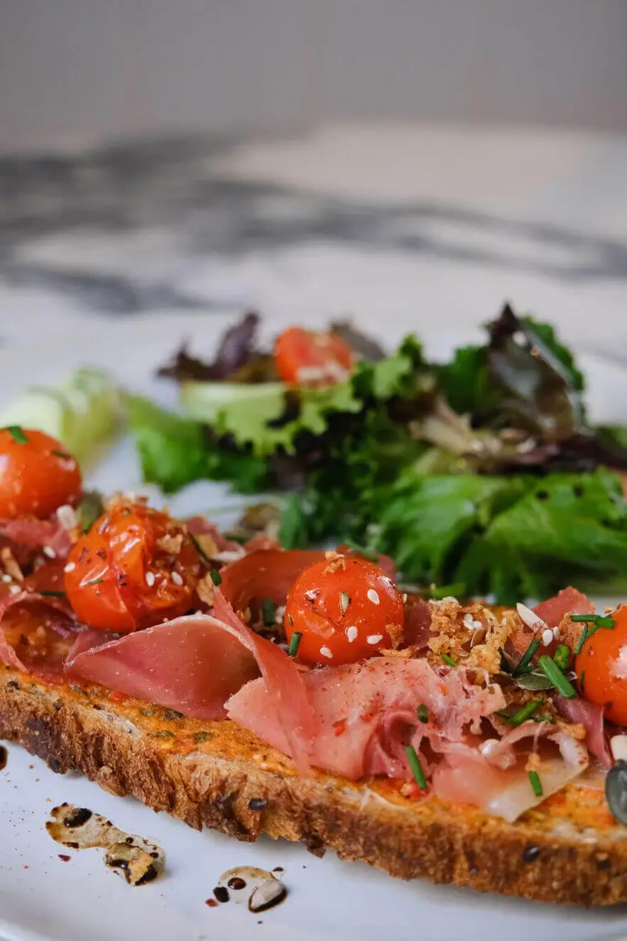 Delicious brunch dish with cherry tomatoes, cured meat, and greens served at Hello, Kristof