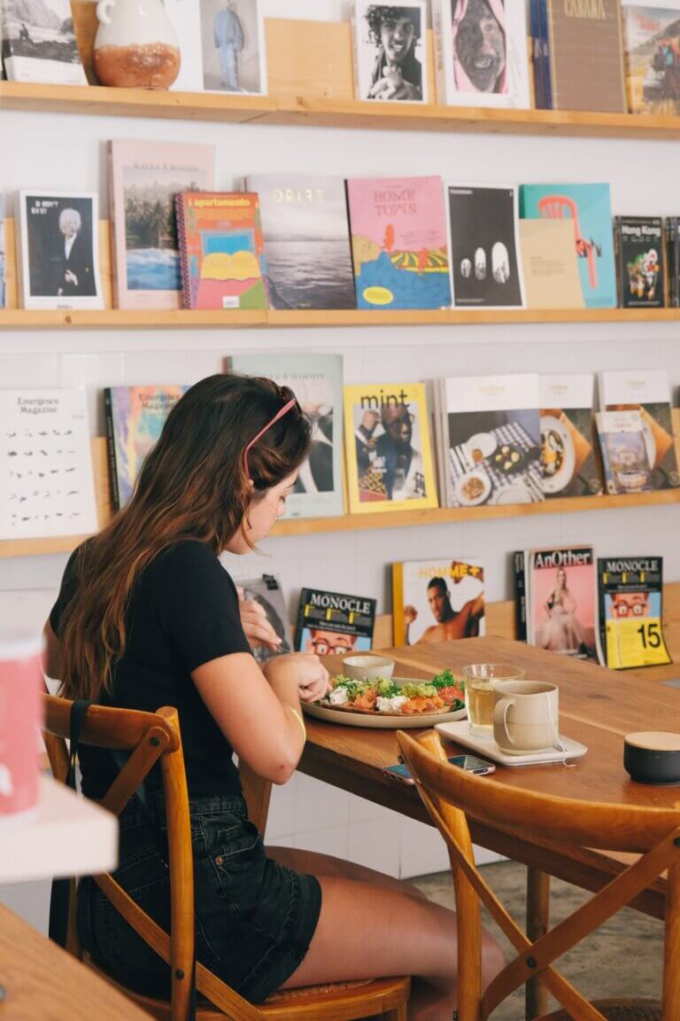 Customer enjoying a meal at a table surrounded by books and magazines at Hello, Kristof