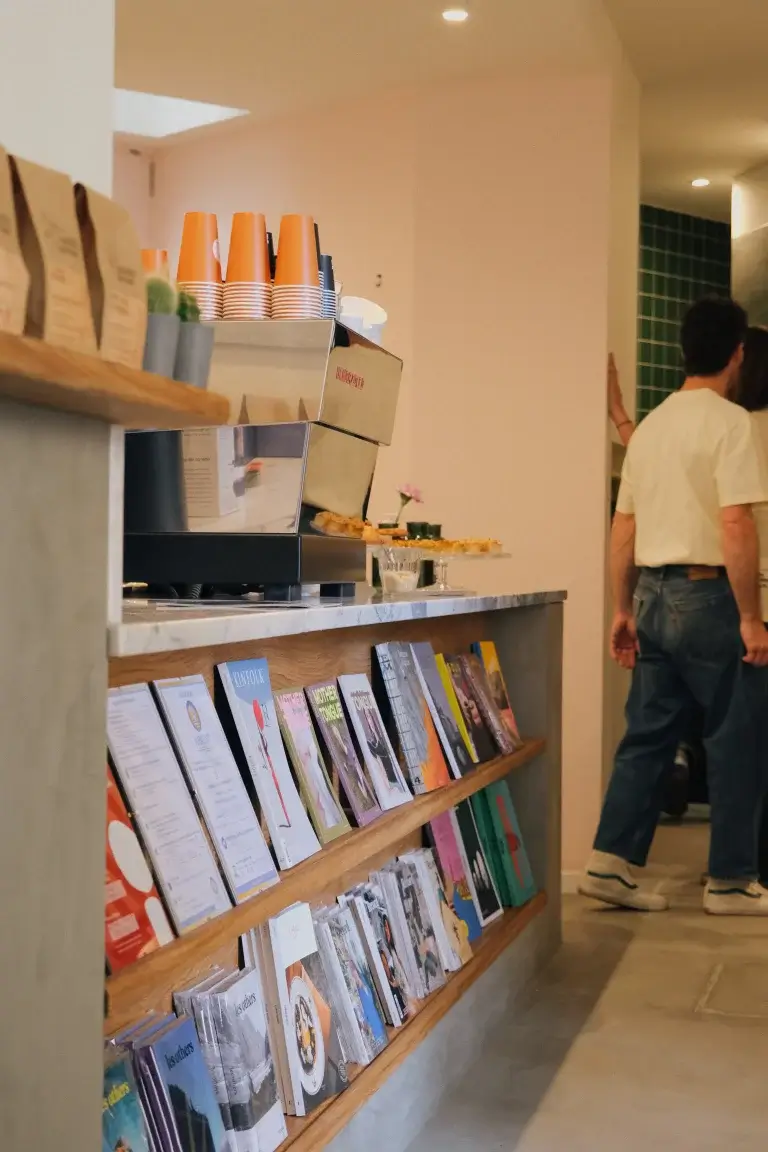 Books and magazines neatly arranged on wooden shelves inside Hello, Kristof