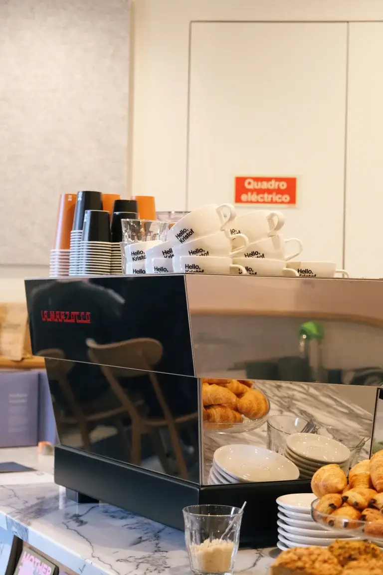 La Marzocco espresso machine with Hello, Kristof branded cups and pastries displayed on the counter at Hello, Kristof coffee shop