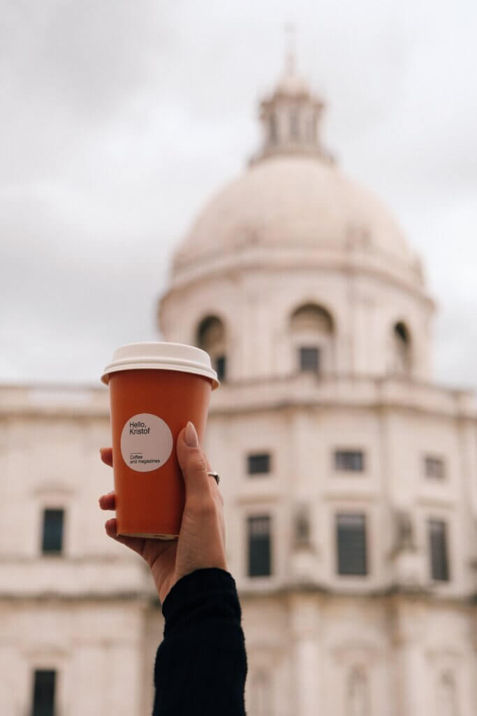 Hand holding a Hello, Kristof coffee cup with the Pantheon dome in the background