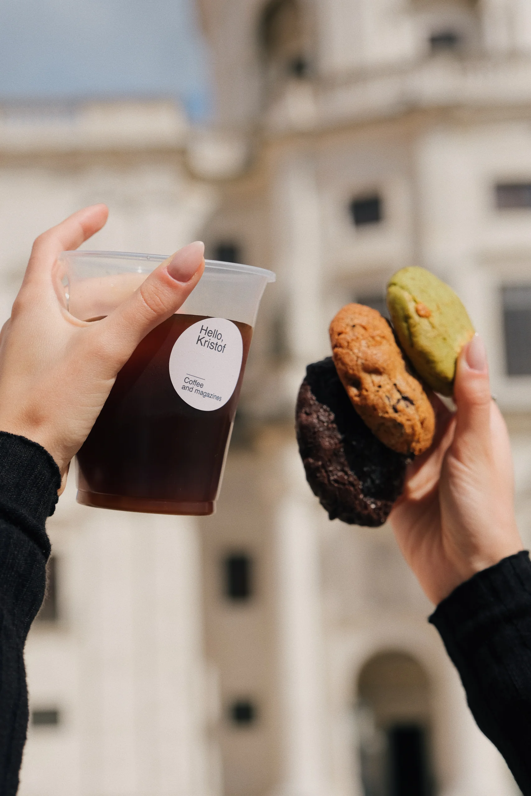 Hand holding a cup of iced coffee and cookies with the Pantheon in the background