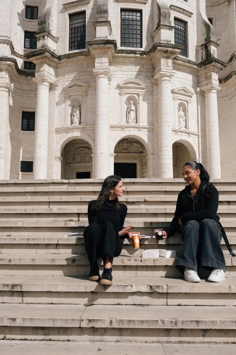 Two people sitting on steps enjoying coffee with the Pantheon in the background