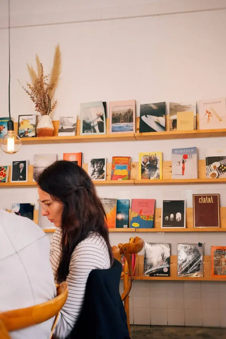 Customer sitting at a table with books and magazines displayed on shelves in the background at Hello, Kristof